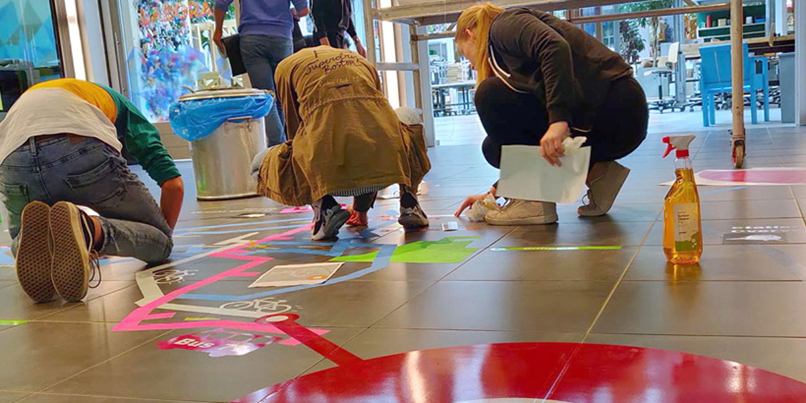 Young people adding colourful stickers to a tiled floor, showing different routes and pictograms